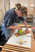 Load image into Gallery viewer, Artist Dana W. sanding down a wooden charcuterie board