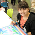 Load image into Gallery viewer, Artist Kim D. looks up from painting a floral watercolor piece of art